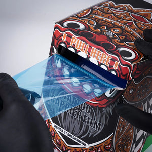 Pulling a sheet from Dragonhawk Tattoo Barrier Film dispenser box.
