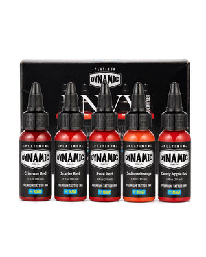 A set of five Dynamic Platinum Envy tattoo ink bottles in front of their black packaging box, featuring shades of Crimson Red, Scarlet Red, Pure Red, Sedona Orange, and Candy Apple Red. Each bottle is 1 fl oz (30ml).