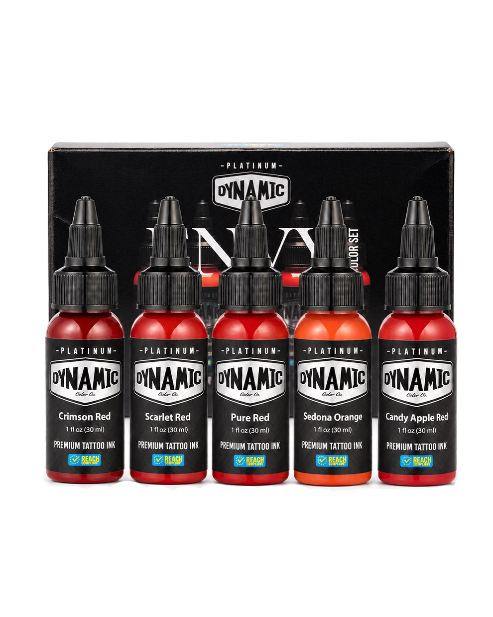 A set of five Dynamic Platinum Envy tattoo ink bottles in front of their black packaging box, featuring shades of Crimson Red, Scarlet Red, Pure Red, Sedona Orange, and Candy Apple Red. Each bottle is 1 fl oz (30ml).