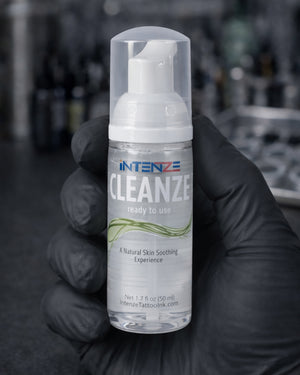 Intenze Cleanze tattoo cleansing foam 50ml bottle held by tattoo artist in studio setting, Coz Tattoo Supplies