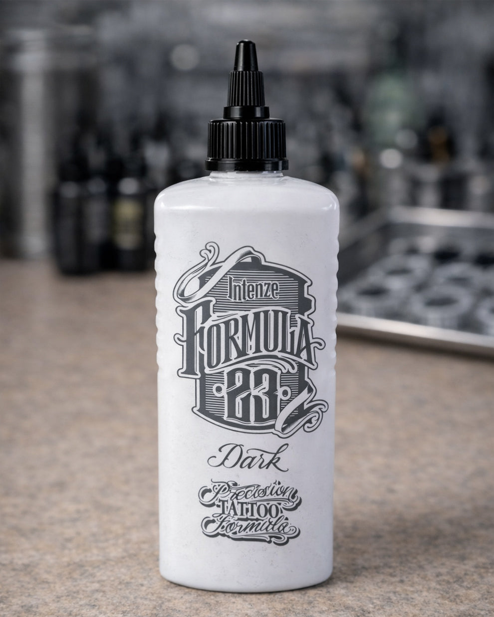 Intenze Formula 23 Dark tattoo ink bottle standing on a tattoo artist workstation, professional studio lighting, Coz Tattoo Supplies