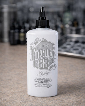 Intenze Formula 23 Light tattoo ink bottle on tattoo artist workstation, professional studio setup by COZ Tattoo Supplies