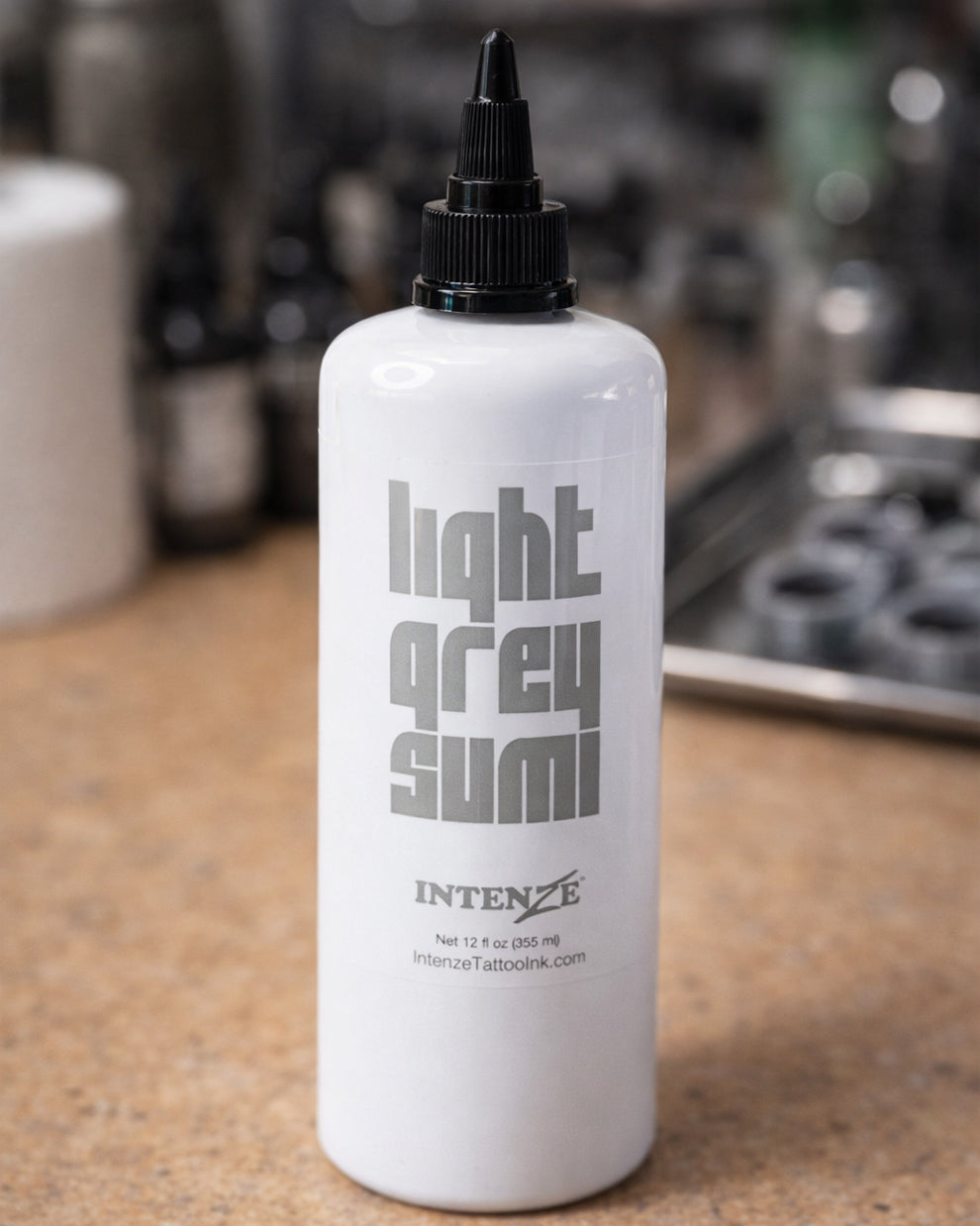 Intenze Light Grey Sumi grey wash tattoo ink held by a tattoo artist in black gloves, professional studio photo, 12 oz bottle – Coz Tattoo Supplies