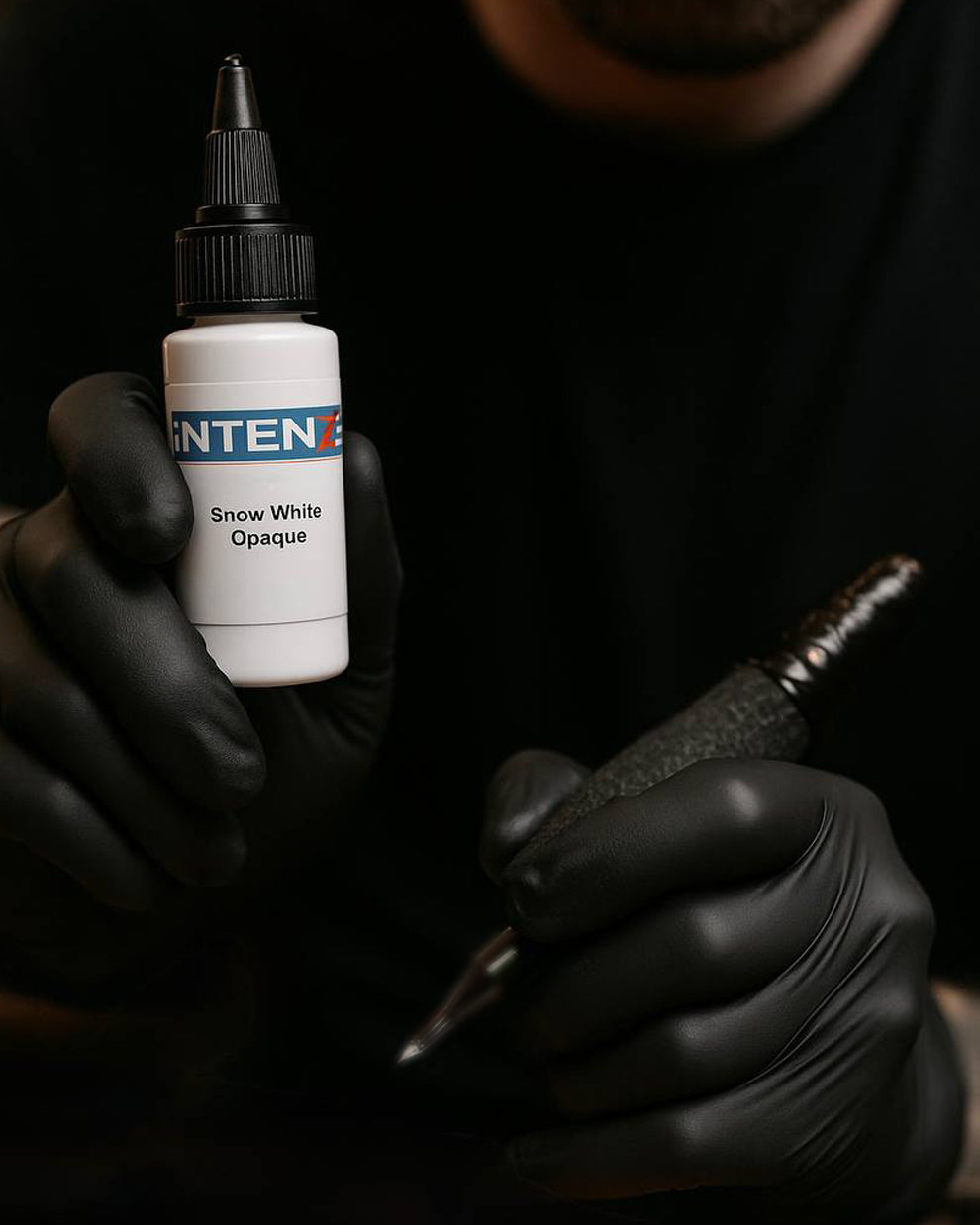 Tattoo artist holding Intenze Snow White Opaque Ink – ideal for highlights, blending, and smooth white saturation.