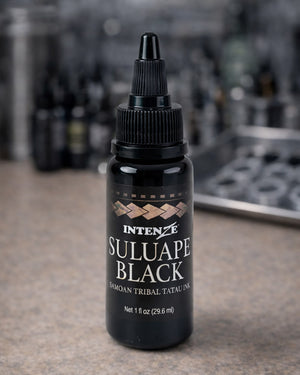 Intenze Suluape Black Samoan tribal tattoo ink 1 oz bottle on a tattoo artist workstation table