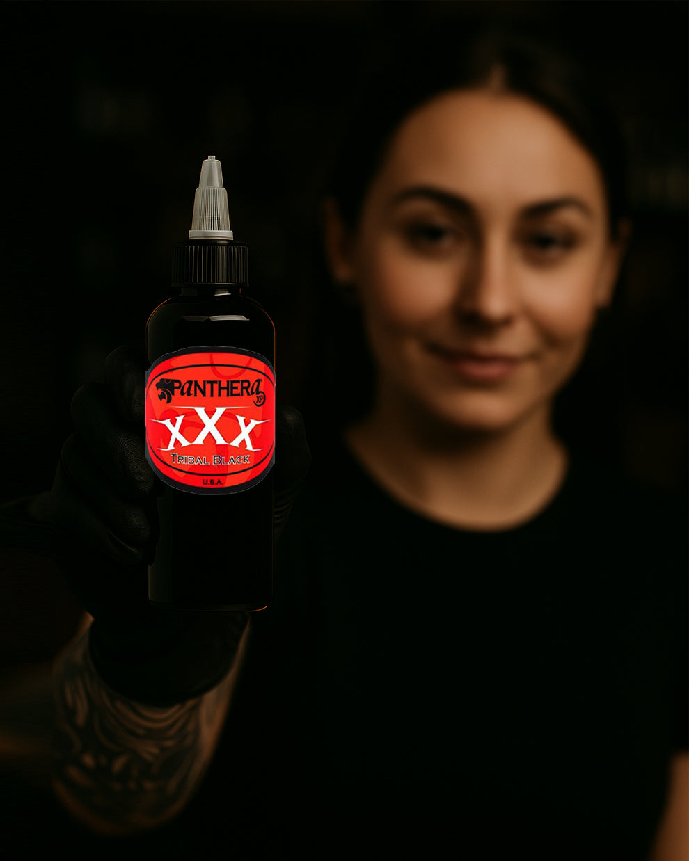 Tattoo artist holding a bottle of Panthera XXX Tribal Black Tattoo Ink – premium black ink for deep fills and bold lines.
