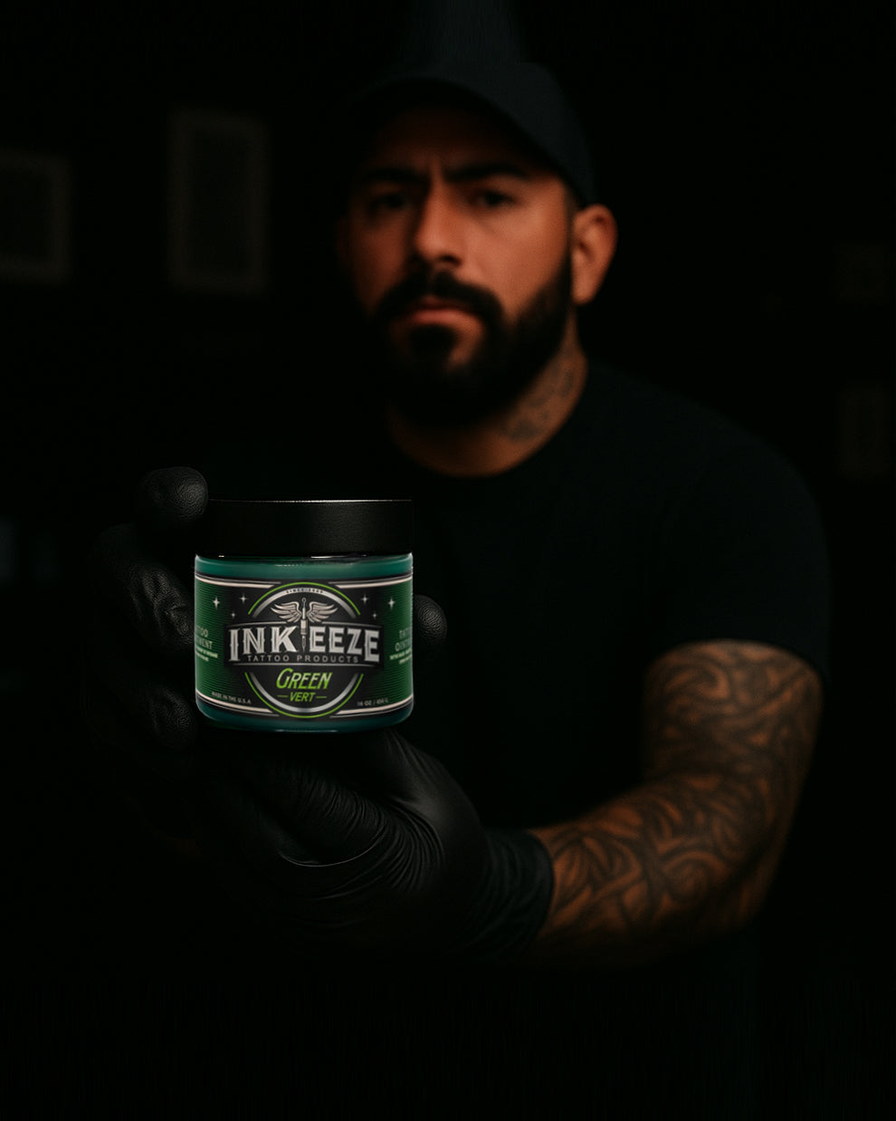 Tattoo artist holding INK-EEZE Green Tattoo Ointment 16oz Jar by COZ Tattoo Supplies Canada — professional vegan tattoo aftercare balm for healing fresh tattoos
