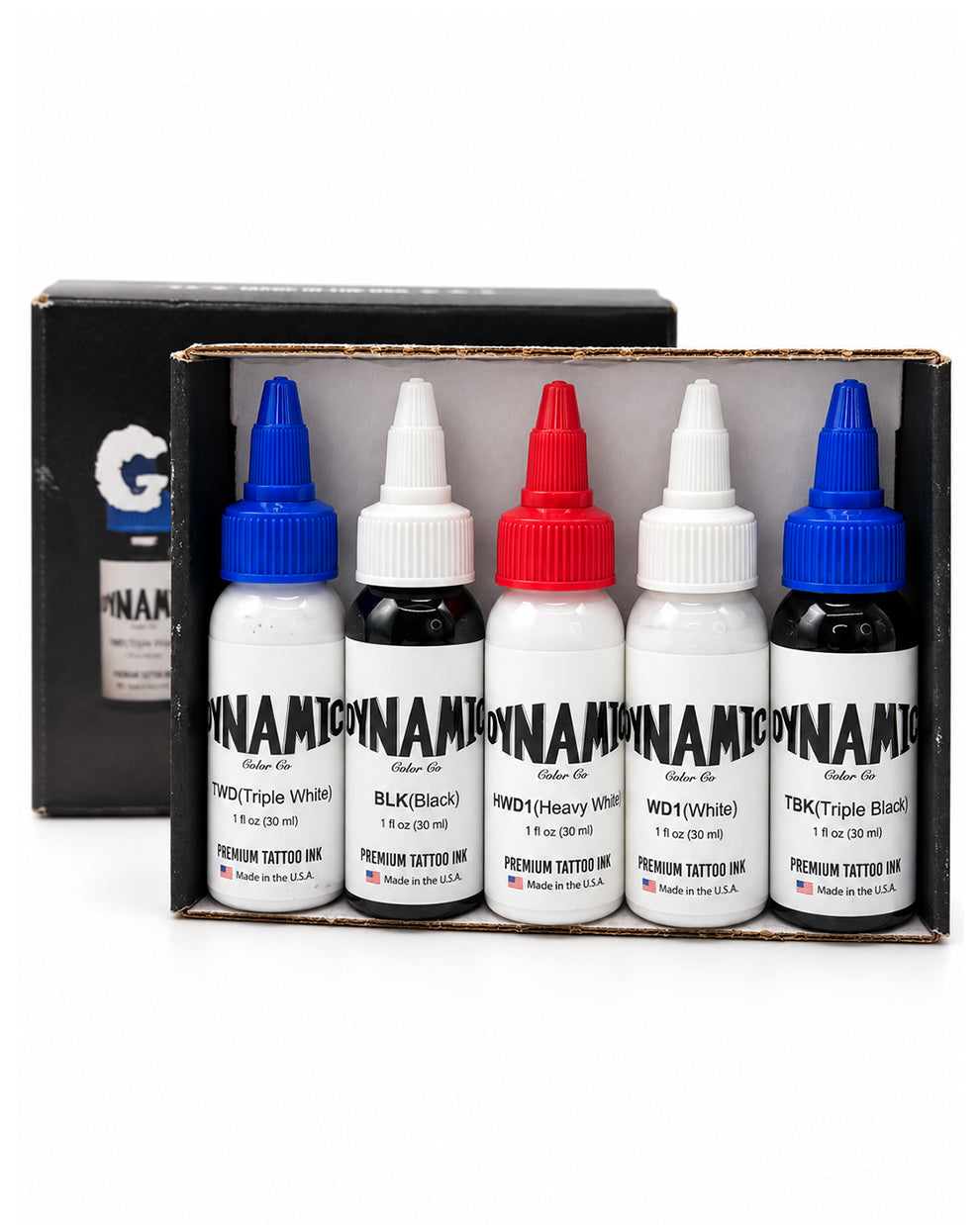 A set of premium tattoo ink bottles displayed in their cardboard tray packaging, with a black branded outer box behind them. The bottles are labeled Dynamic Tattoo Ink and include colors Triple White, Black, Heavy White, and Triple Black.