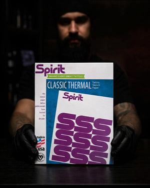 Tattoo artist holding Inkjet stencil paper pack on black tattoo workstation, professional studio setup