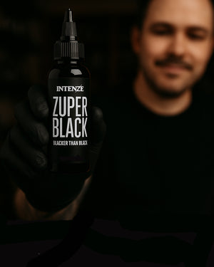 Tattoo artist proudly holding Intenze Zuper Black Tattoo Ink – premium black tattoo ink for professionals, ideal for bold lines and deep shading.