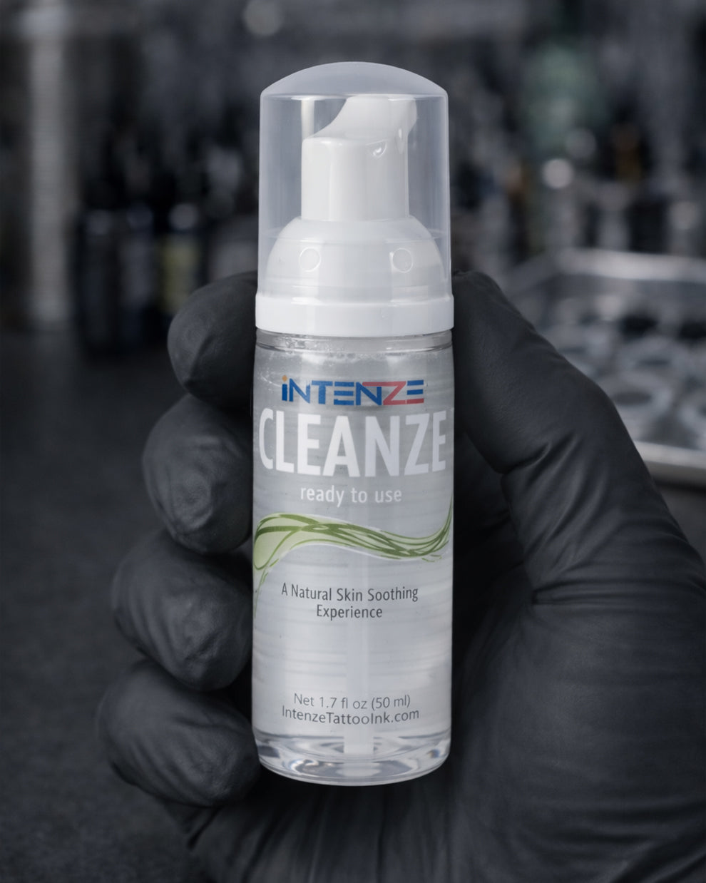 Intenze Cleanze tattoo cleansing foam 50ml bottle held by tattoo artist in studio setting, Coz Tattoo Supplies