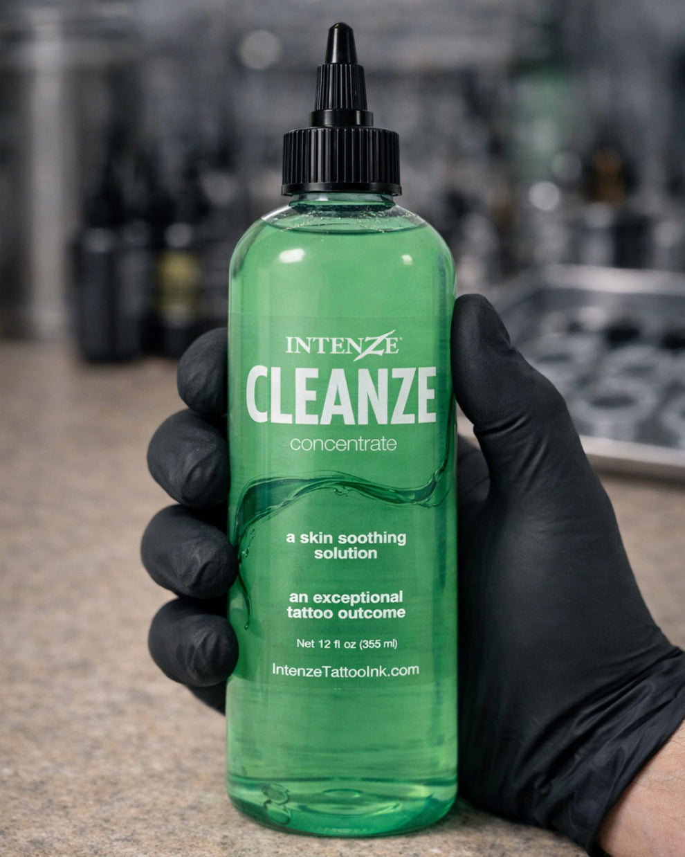 Intenze Cleanze Concentrate 12 oz bottle held by tattoo artist in black glove, professional tattoo aftercare solution, Coz Tattoo Supplies
