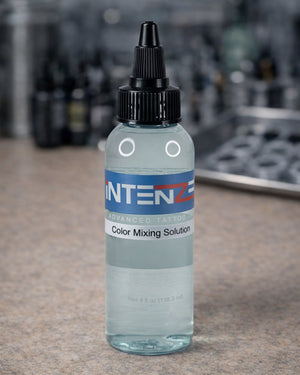 Intenze Color Mixing Solution 4 oz placed on tattoo artist workstation table, professional tattoo studio setting by Coz Tattoo Supplies