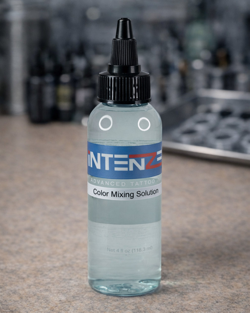 Intenze Color Mixing Solution 4 oz placed on tattoo artist workstation table, professional tattoo studio setting by Coz Tattoo Supplies
