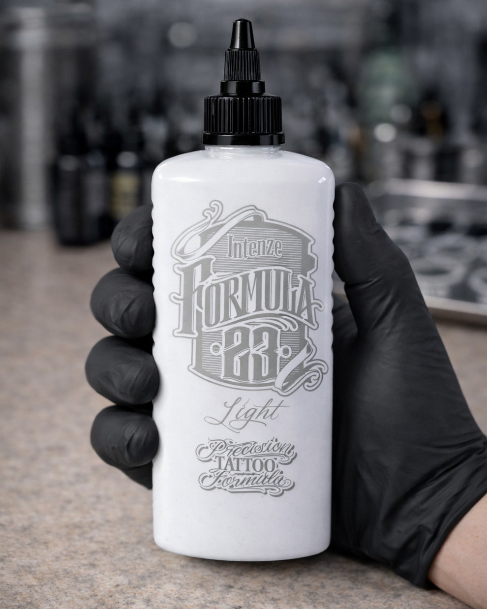 Tattoo artist holding Intenze Formula 23 Light tattoo ink bottle 12oz, professional studio photo by COZ Tattoo Supplies