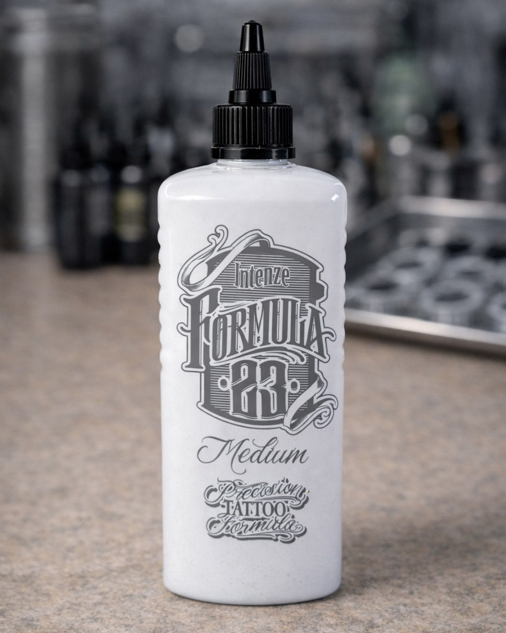 Intenze Formula 23 Medium tattoo ink bottle placed on a tattoo artist workstation, professional studio setup by COZ Tattoo Supplies