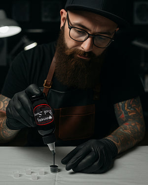 Tattoo artist pouring Panthera Dark Sumy Tattoo Ink into an ink cap, showcasing precision and professional-grade pigment in a studio environment.
