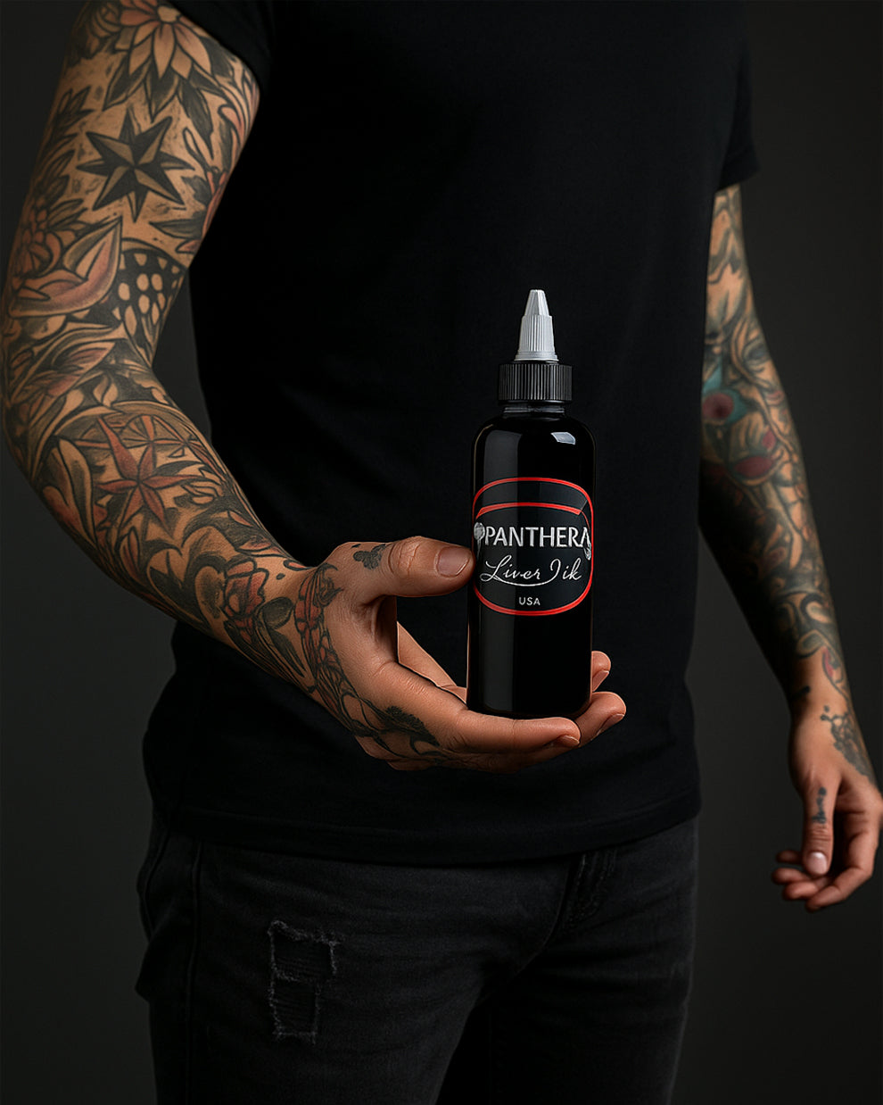 Tattoo artist holding Panthera Liner Dark Tattoo Ink 5oz bottle – trusted black ink for precise tattoo outlines.